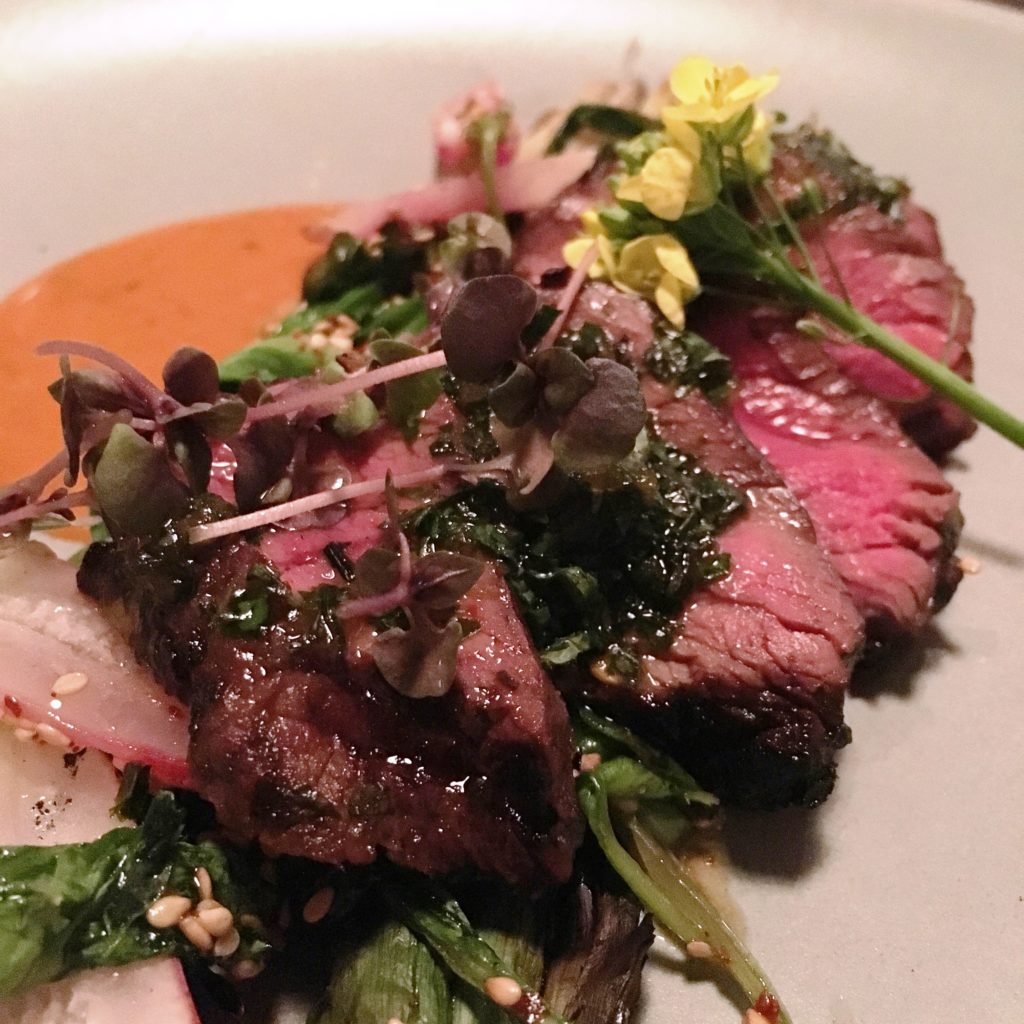 CHANGING STEAK OPTION, typically seared and served over charred greens. This one had edible flowers, radishes and a flavorful sauce. A meat option is always on the menu. 