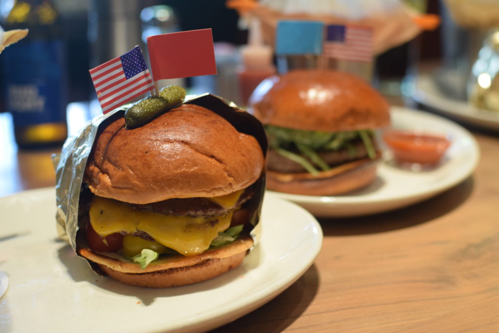 Trump burger in the front, complete with gold foil wrapping and a tiny pickle on top. 